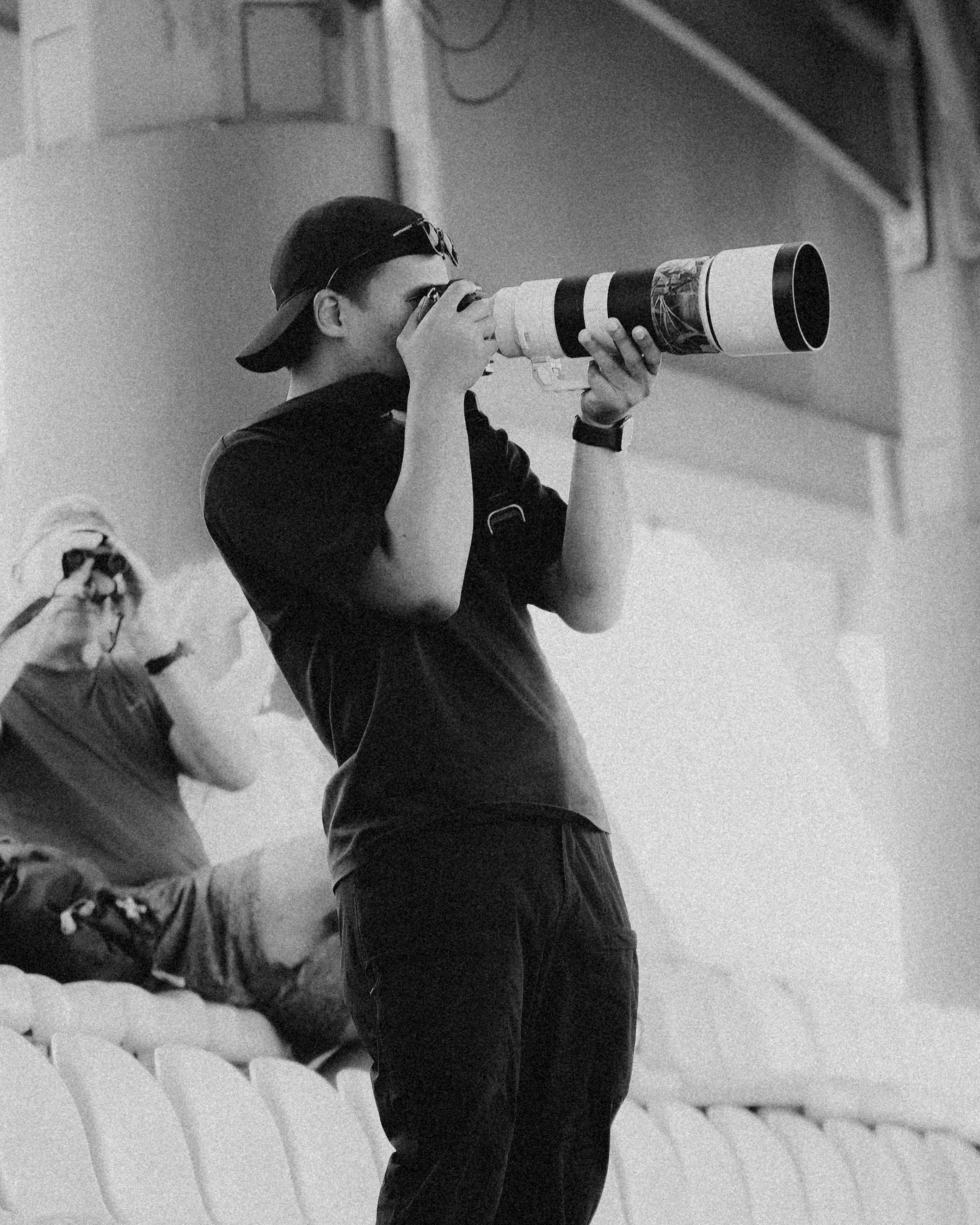 Photographer looking through a camera with a long telephoto lens.